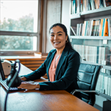 woman smiling, looking away from a computer