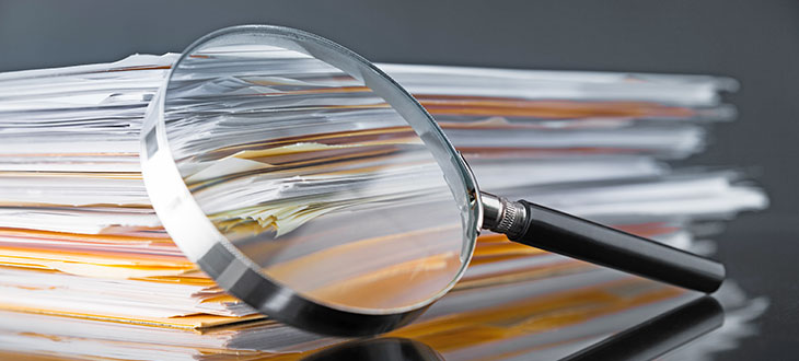 magnifying glass propped up against stack of journal articles