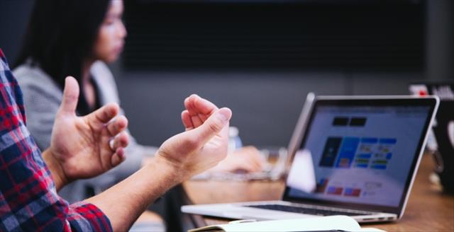 Man's hands gesturing in front of computer