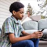 Adolescent sitting on a porch and looking at a smartphone.