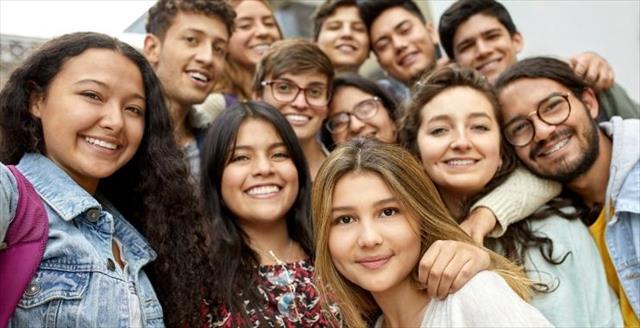 Teens hugging and smiling outside.