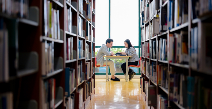 Young man and woman collaborating on an educational project in a peaceful university library