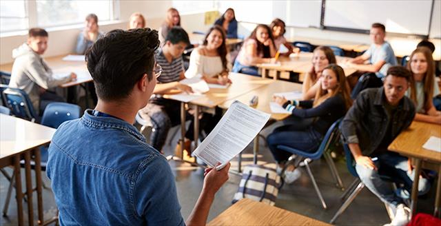 Teacher presents topic in front of classroom of high school students.