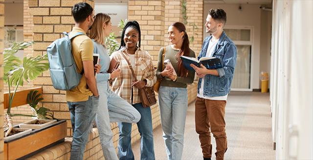 Diverse group of high school students stand outside school engaged in conversation.