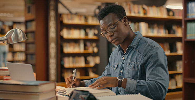 African man sitting inside a library alone doing research.