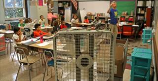 This image shows a box fan positioned at the front of a classroom to improve ventilation