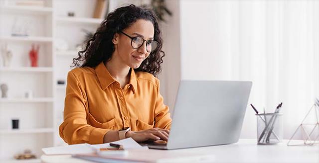 Woman with glasses glancing at her laptop