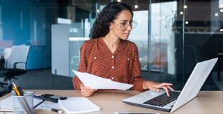 Young happy and successful businesswoman in glasses working with documents inside office