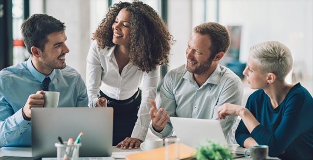 Man smiling at colleague and holding coffee cup