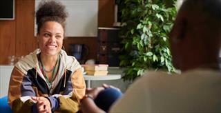 A counseling session showing two people seated and facing each other.