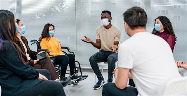 Young people wearing masks seated in an open circle having a discussion