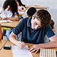 High school students seated at desks taking a paper-based test.